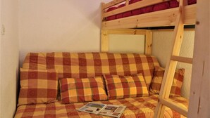 A bunk bed with a checkered bedspread and pillows, a ladder, and a magazine on the bed. - 50m from ski slopes, 5th floor, balcony, tv, ski locker, 23m², Risoul (Risoul)