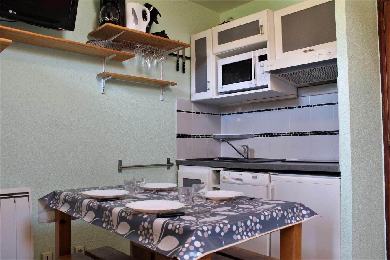 A compact kitchen with a microwave, stove, and a dining table set for four.