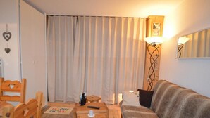 A cozy living room with a sofa, wooden chairs, a small table, and a lamp. - 10m from ski slopes, 7th floor, view mountain, balcony, tv, 22m², Les Menuires (Les Menuires)