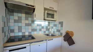 A compact kitchen with a sink, a microwave, and a dishwasher. - 10m from ski slopes, 7th floor, view mountain, balcony, tv, 22m², Les Menuires (Les Menuires)