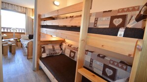 A cozy room with bunk beds, a wooden desk, and a window with curtains. - 10m from ski slopes, 7th floor, view mountain, balcony, tv, 22m², Les Menuires (Les Menuires)