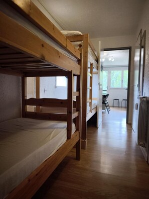 Una camera con letto a castello, pavimento in legno e vista su una sala da pranzo.
