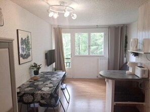 Una cucina compatta con zona pranzo, una finestra con tende e una lampada a sospensione.