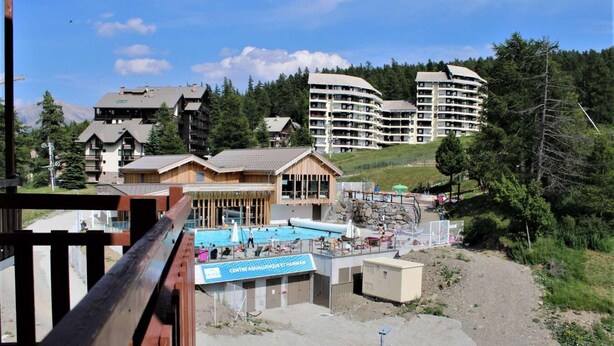 Un resort con piscina, varias edificaciones y montañas al fondo.