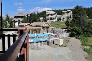 A resort with a swimming pool, multiple buildings, and a mountainous backdrop.
