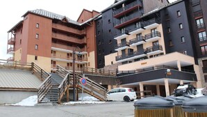 Un hotel de varios pisos con balcones y un área de estacionamiento.
