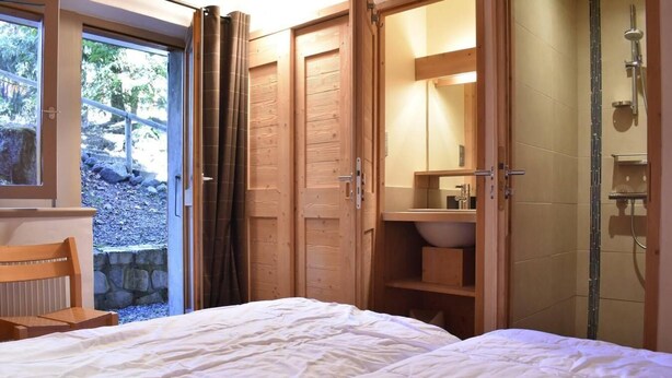 Une chambre à coucher avec un lit, une armoire en bois et une salle de bain avec douche.