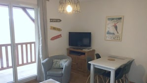 Ett vardagsrum med en tv, ett matbord och en soffa. Det finns skyltar på väggen och en affisch på väggen.