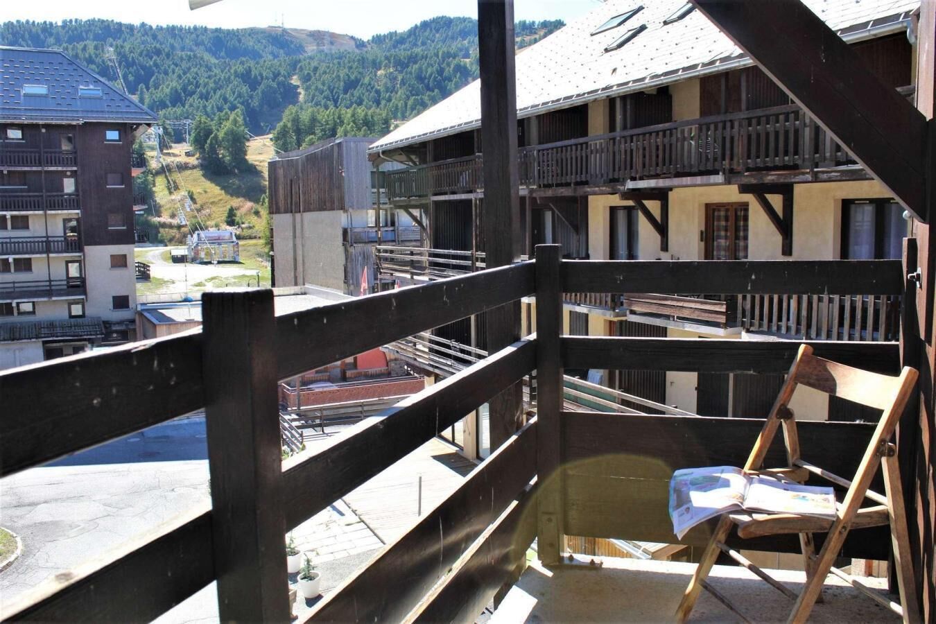 Un balcon doté d’une balustrade en bois, donnant sur une région montagneuse.