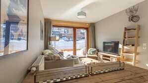 Un salon avec un canapé, un téléviseur, une table basse en bois et une bibliothèque.
