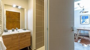 Une salle de bain moderne avec un meuble-lavabo en bois, un grand miroir et un espace douche.