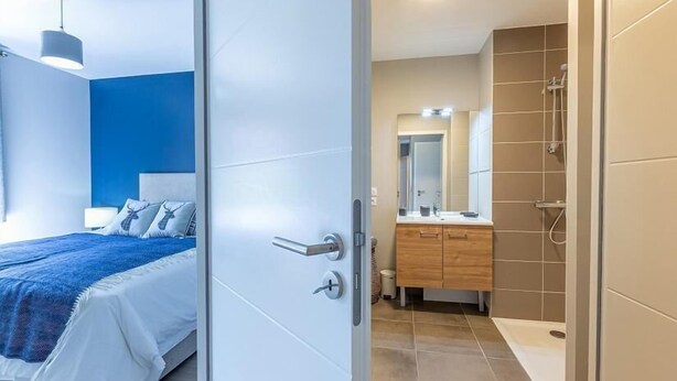 Une chambre à coucher moderne avec un lit, une table de chevet et une petite table d’appoint.