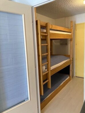 A bunk bed with a ladder in a room with a door and a window.