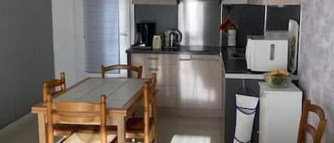 A compact living space with a dining area, kitchenette, and a sofa with a pillow.