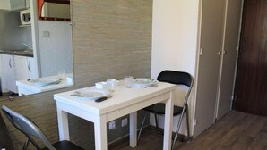 A small, clean room with a white table set for two, a black chair, a microwave, and a door. - 100m from ski slopes, 3rd floor, tv, ski locker, 18m², Vars (Vars)