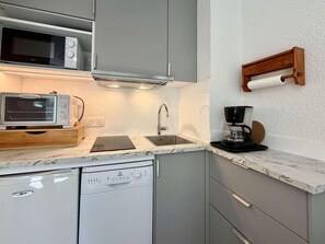 Cocina compacta equipada con microondas, tostadora, cafetera y lavavajillas.
