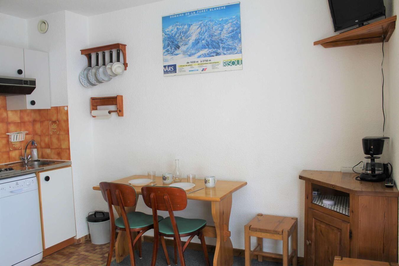 Une cuisine compacte équipée d’un évier, d’une cuisinière et d’un petit coin repas avec deux chaises.