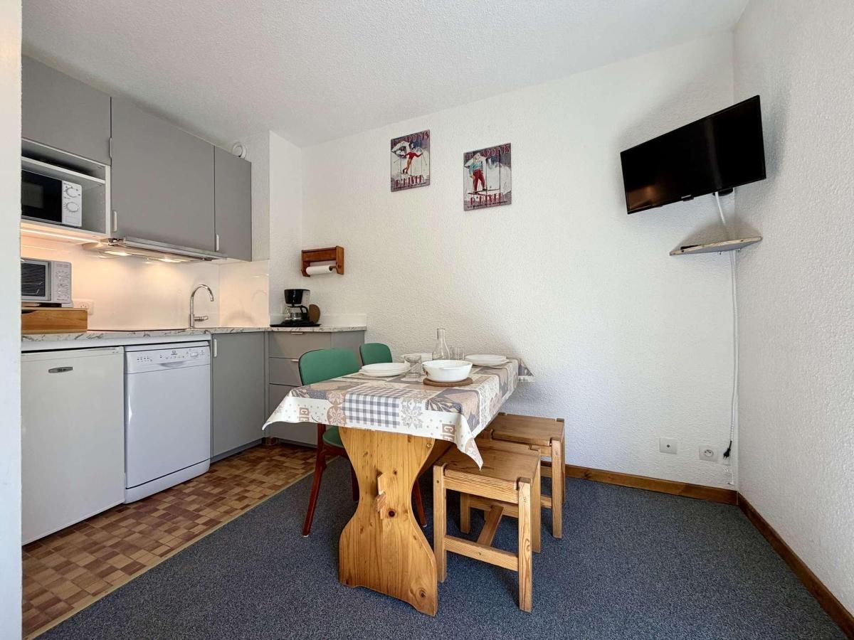 Cocina compacta con comedor, microondas, lavavajillas y un televisor de pantalla plana montado en la pared.