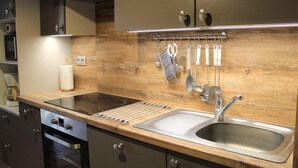 Une cuisine moderne avec un revêtement mural en bois, des appareils en acier inoxydable et des ustensiles de cuisine accrochés au mur.