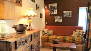 Una sala de estar acogedora con un aparador de madera, una mesa, un sofá y una lámpara.