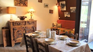 Un comedor con una mesa de madera dispuesta para cuatro, un aparador antiguo y un sofá al fondo.
