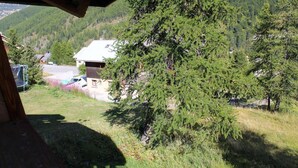 Una casa de techo inclinado, rodeada de un bosque tupido y un cielo despejado.