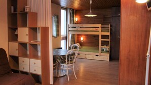 Tunnelmallinen huone, jossa on kerrossänky, puinen työpöytä, tuoli ja kirjahylly.