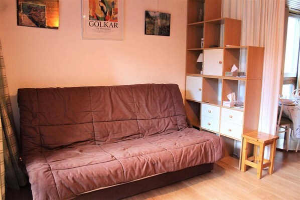 A room with a brown sofa, a wooden cabinet, and a small wooden stool.