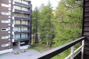 A multi-story building with balconies, surrounded by dense forest.