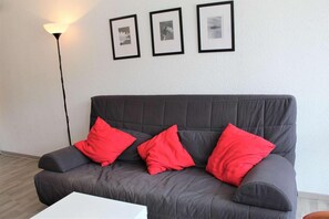 A grey sofa with three red cushions, a white table, and three framed pictures on the wall. - 100m from resort center, 1st floor, balcony, parking, tv, 28m², Vars (Vars)