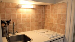 A kitchen with a stainless steel sink, a white countertop, and a built-in stove.