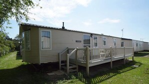 A mobile home with a deck and a staircase leading to the entrance. - Cozy  2 bedroom Coastal Chalet in Hunstanton (Hunstanton)