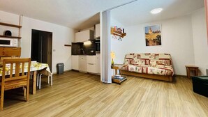 Un espacio habitable compacto con kitchenette, comedor y sofá.