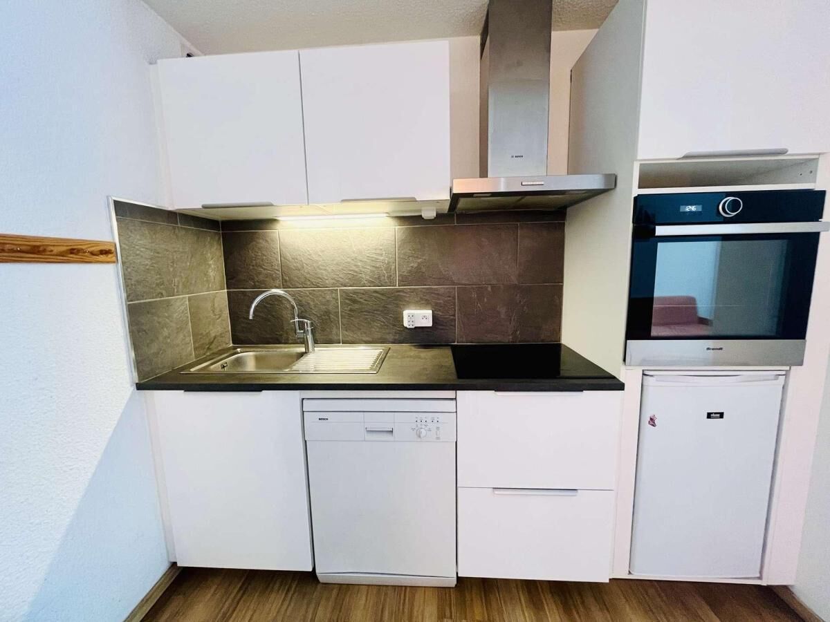A compact kitchen with a dishwasher, sink, and built-in oven.