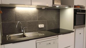 Una cocina con lavavajillas Bosch, un lavabo con grifo moderno y un horno empotrado.