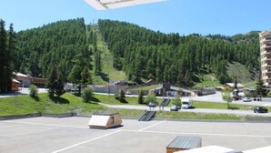 Un área de estacionamiento con vistas a una montaña, un telesilla y un edificio con un letrero que dice "Vares".