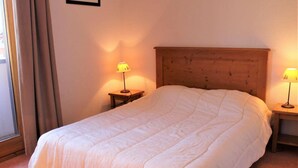 A neatly made bed with a wooden headboard, two bedside tables with lamps, and a window with curtains. - 100m from ski slopes, Ground floor, terrace, tv, 72m², Vars (Vars)
