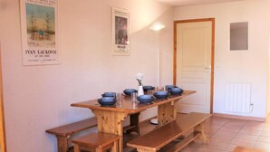 A dining area with a wooden table set for four, benches, and a white floor lamp. - 100m from ski slopes, Ground floor, terrace, tv, 72m², Vars (Vars)