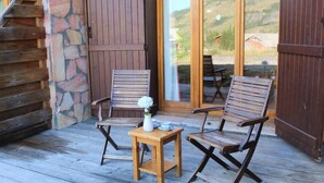 A wooden deck with two chairs and a small table, a stone wall, and a wooden door. - 100m from ski slopes, Ground floor, terrace, tv, 72m², Vars (Vars)