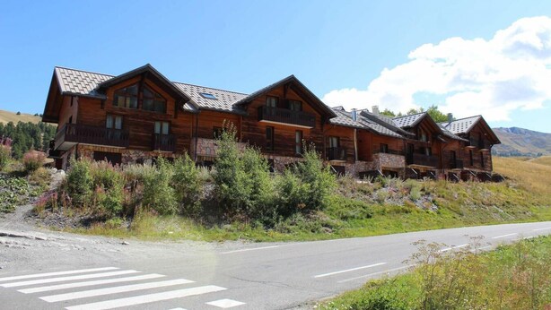 A wooden lodge with multiple balconies and a stone foundation, set in a mountainous area with a clear road in front. - 100m from ski slopes, Ground floor, terrace, tv, 72m², Vars (Vars)