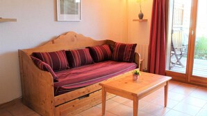 A wooden sofa with striped cushions, a wooden coffee table, a framed picture on the wall, and a sliding glass door leading outside. - 100m from ski slopes, Ground floor, terrace, tv, 72m², Vars (Vars)