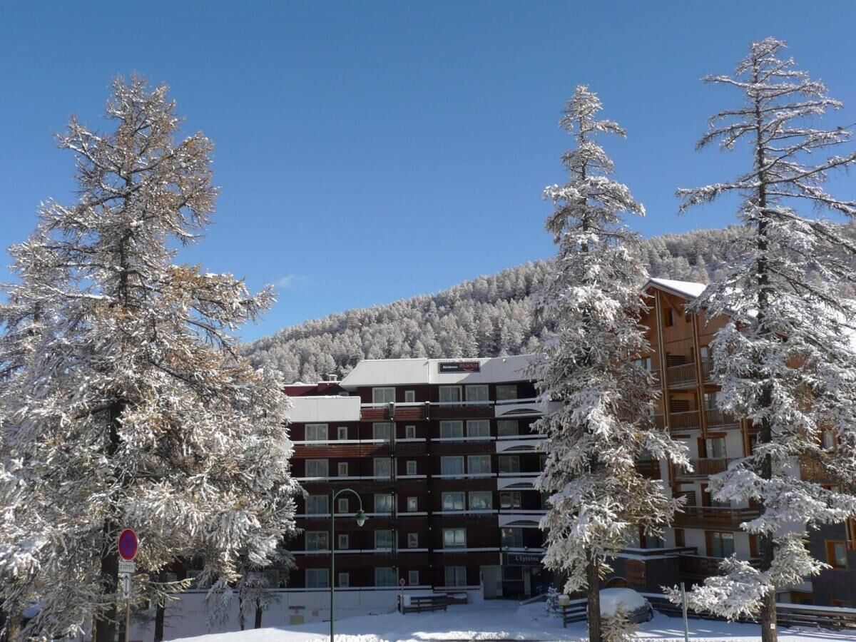 Un hotel a più piani con un paesaggio innevato, circondato da alberi.