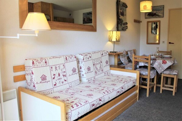 A cozy room with a wooden sofa, a dining table with chairs, and a mirror on the wall. - 200m from resort center, 5th floor, view mountain, balcony, tv, 25m², Vars (Vars)