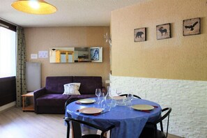 Cozy living space with a dining area, featuring a sofa, side table, and dining table set.