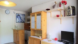 A compact living space with wooden cabinets, a television, and a kitchen area. - 100m from ski slopes, 4th floor, balcony, tv, ski locker, 31m², Vars (Vars)