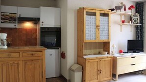 A compact kitchen with a refrigerator, oven, and wooden cabinets. - 100m from ski slopes, 4th floor, balcony, tv, ski locker, 31m², Vars (Vars)