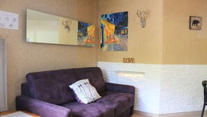 A room with a purple sofa, a small wooden table, and a wall-mounted mirror. - 100m from ski slopes, 4th floor, balcony, tv, ski locker, 31m², Vars (Vars)