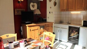 A compact kitchen with wooden cabinets, a small dining table, and a television. - 350m from ski slopes, 3rd floor, balcony, 22m², Vars (Vars)