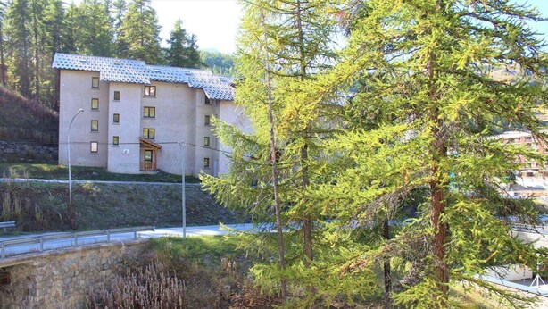 A multi-story building with a tiled roof, surrounded by dense greenery and trees. - 350m from ski slopes, 3rd floor, balcony, 22m², Vars (Vars)