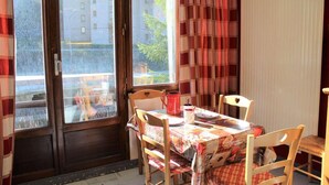 A dining area with a table set for four, wooden chairs, and a window with curtains. - 350m from ski slopes, 3rd floor, balcony, 22m², Vars (Vars)